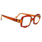 Aptica square reading glass with half-circle shape on top and bottom . Model: Hive. Color: Sticky Honey - Honey orange, Semi-transparent. Side view.